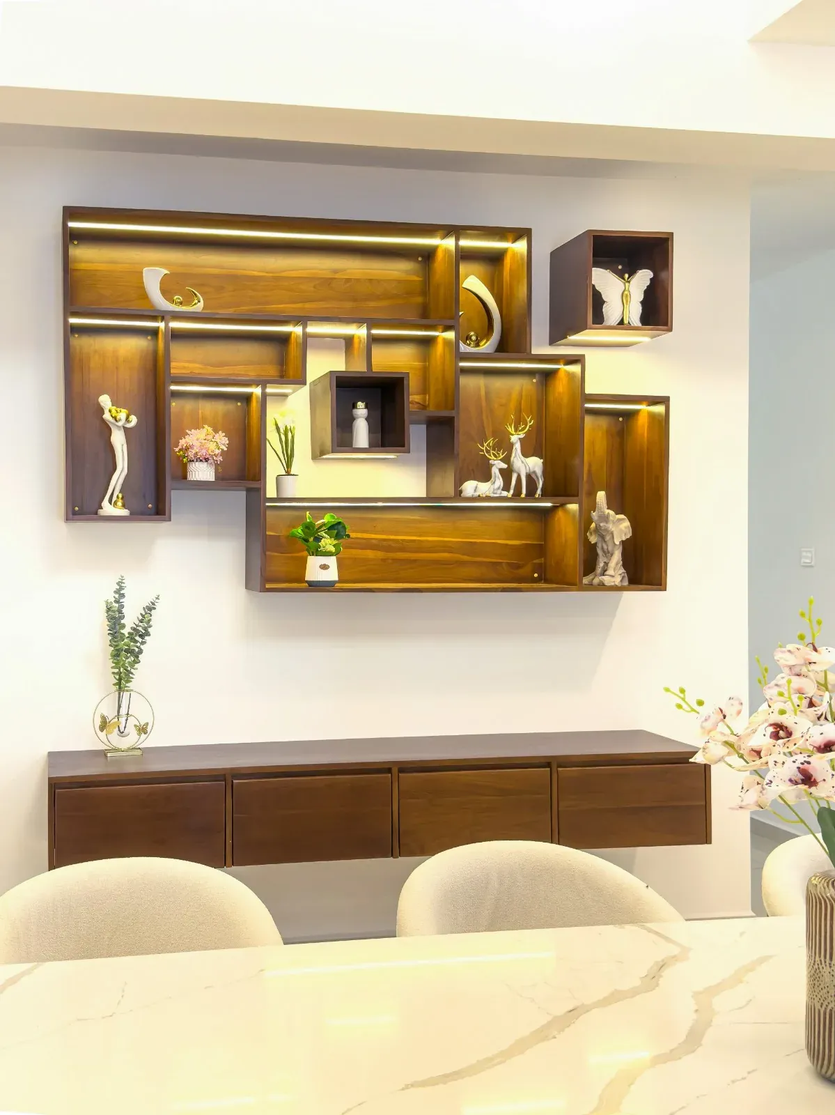 Lit timber display shelving with staggered niches above a floating walnut console
