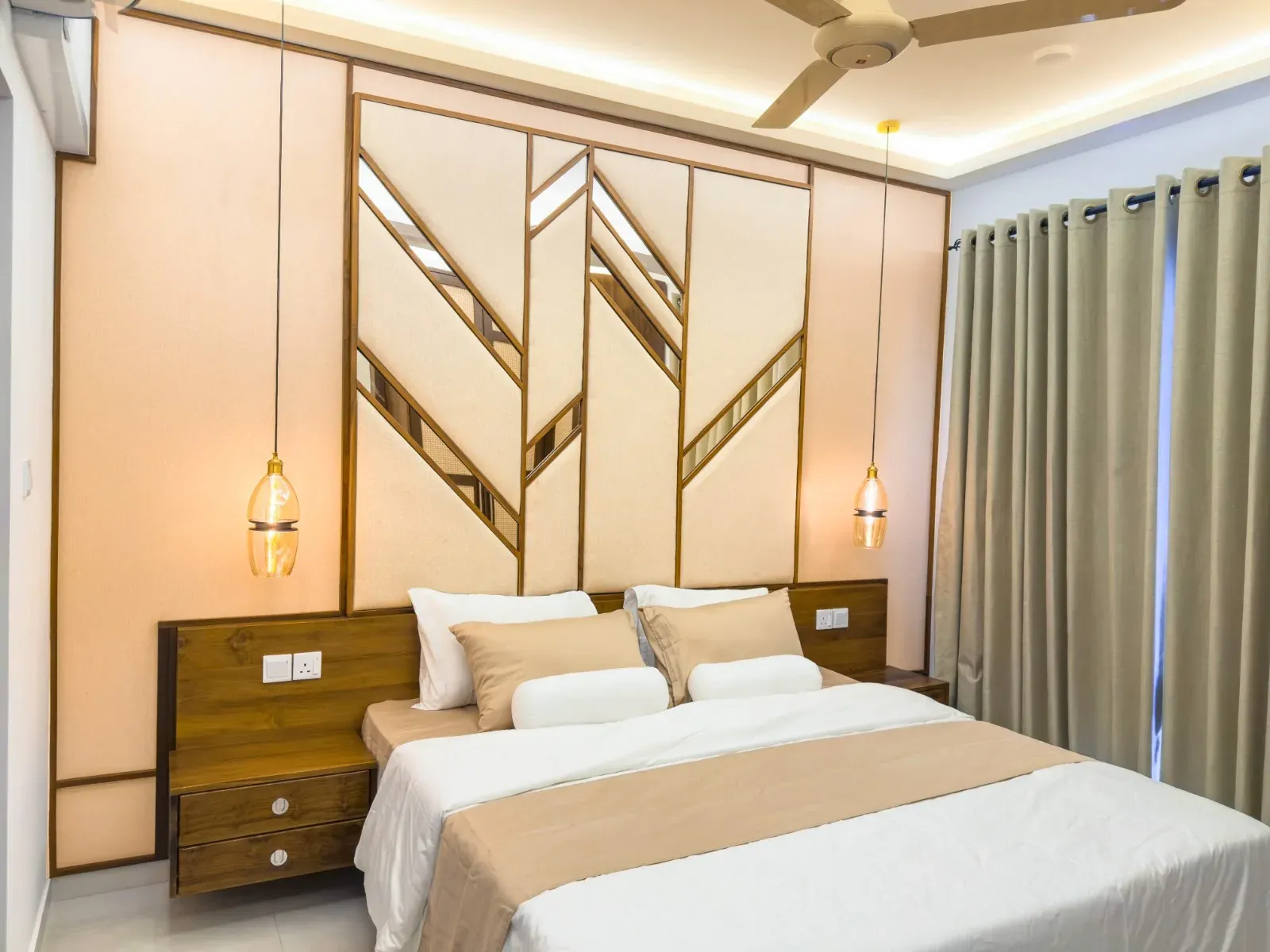 Bedroom with a full-width geometric upholstered headboard inlaid with angled mirror strips