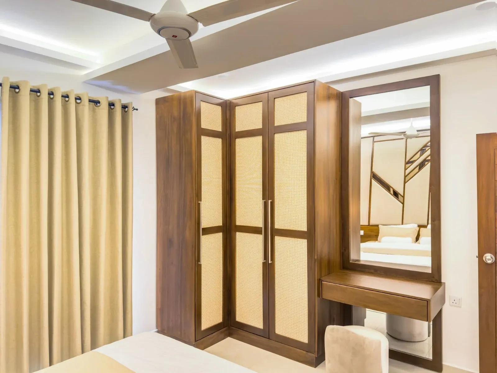 Walnut wardrobe with rattan-cane door panels beside a matching dresser and mirror
