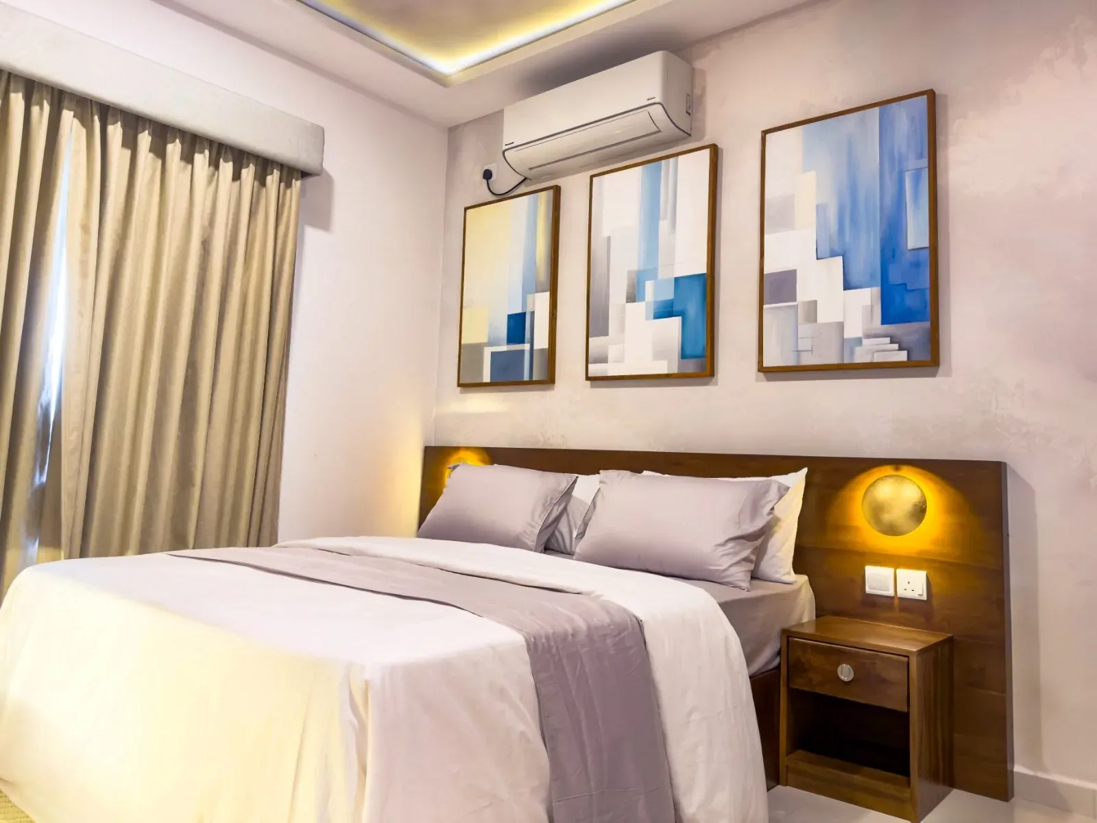 Bedroom with a walnut headboard, wall lights and a set of blue abstract prints