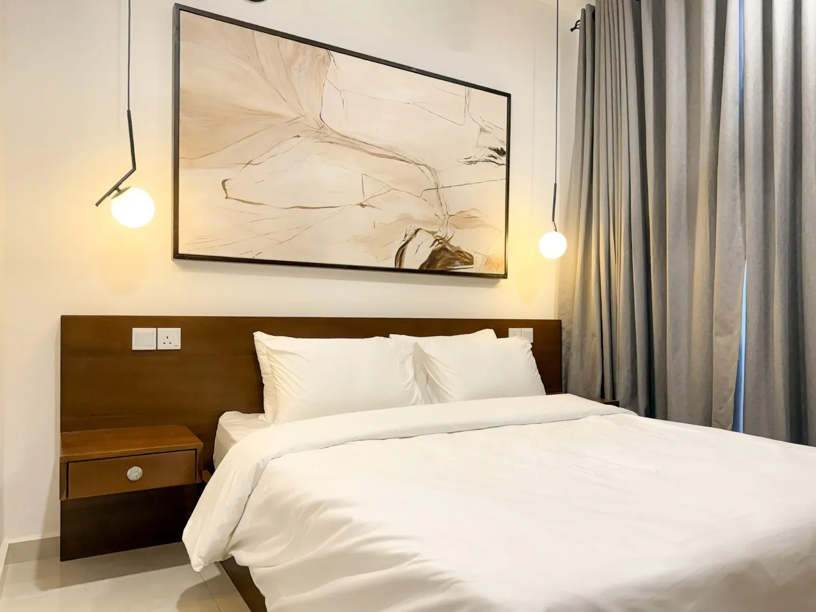 Bedroom with a walnut headboard, globe pendant lights and large abstract artwork