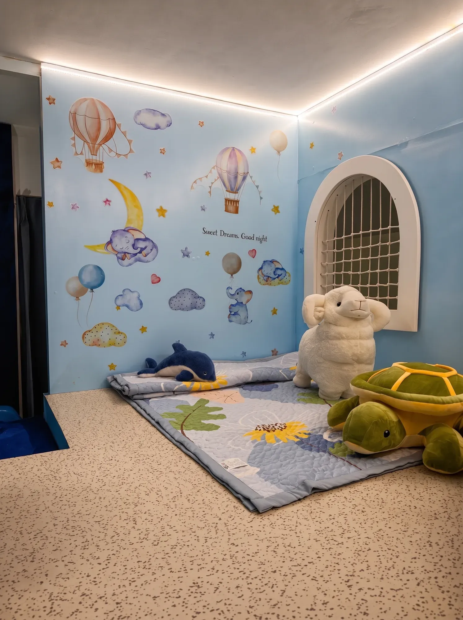 Kids' sleeping nook with a lit ceiling edge and hot-air-balloon wall mural